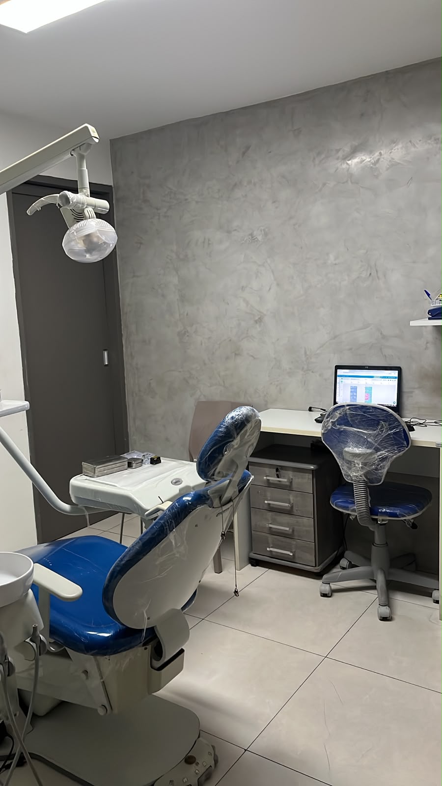 Consultório com cadeira odontológica azul e bancada de atendimento