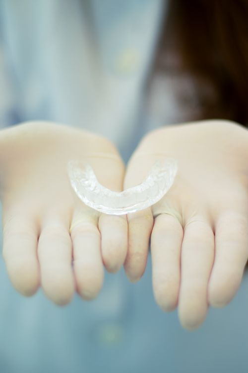 Alinhador transparente apoiado em mãos com luvas